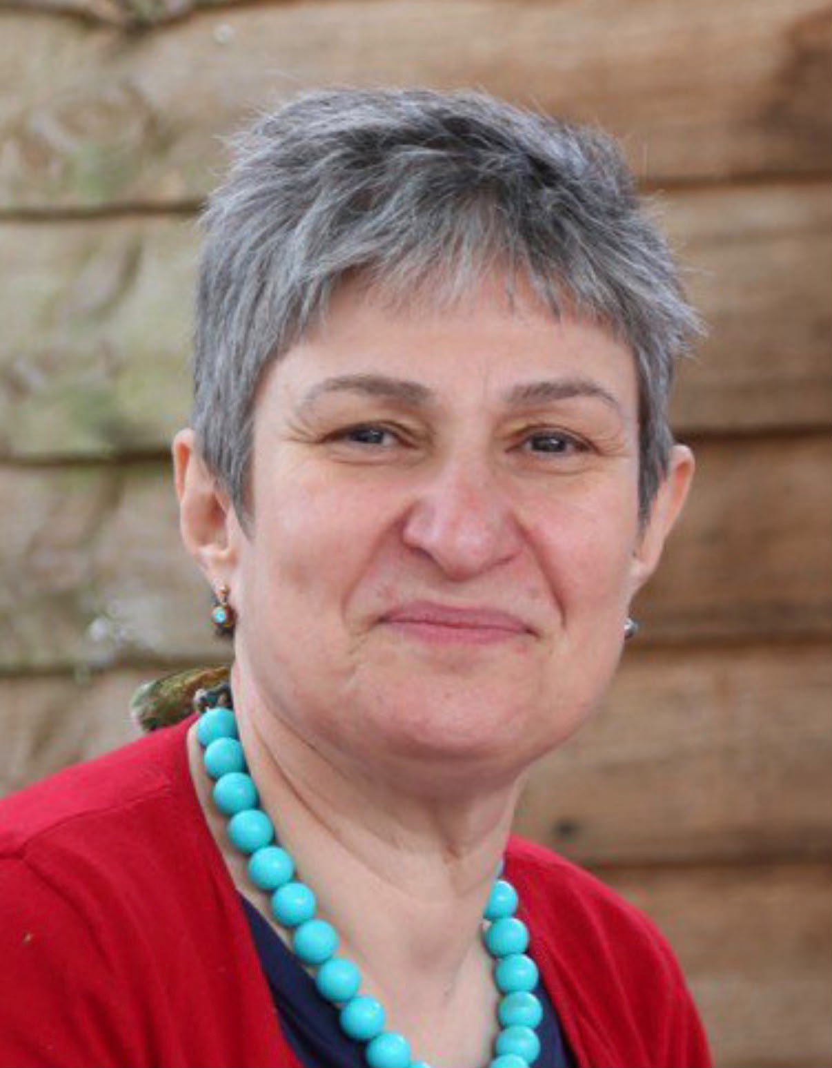 Portrait of Parvin Emampour. Parvin is wearing a red cardigan and a blue necklace.